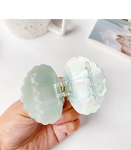 Vue détaillée d'une pince à cheveux en forme de coquillage avec texture nacrée et ressort