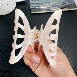 Elegant hollow butterfly hair claw clip with pearlescent pink finish and gold metal spring