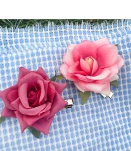 Detail of pink fabric rose hair clips with metal duckbill base on checkered background