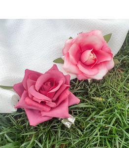 Detail of pink fabric rose hair clips with realistic petals and green leaf accents