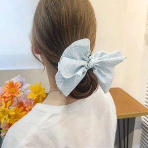 Elegant oversized light blue bow hair scrunchie with white wave stripes on a hair bun