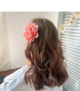 Pince à cheveux fleur en tissu rose portée sur une élégante coiffure ondulée