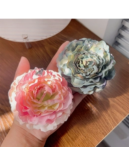 Detail of pink and blue fabric flower hair claws with butterfly center embellishments