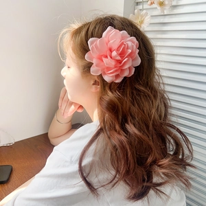 Pince à cheveux fleur camélia en tissu rose portée par un mannequin près de la fenêtre