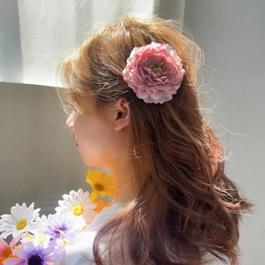 Elegant pink fabric rose flower hair claw clip shown on a model in bright natural light
