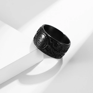 Vintage matte black titanium ring with celestial sun face relief on geometric stand
