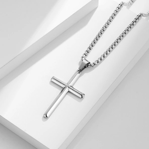 Polished silver stainless steel cross pendant on a classic box chain over white blocks