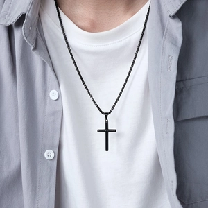 Minimalist black stainless steel cross necklace for men shown on a male model with a white tee