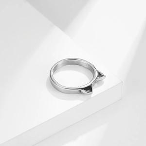 Minimalist silver cat ear ring displayed on a modern white geometric display stand