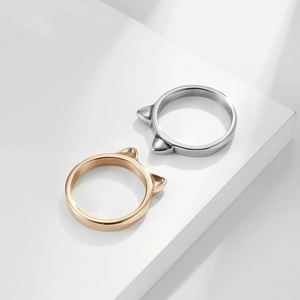 Polished titanium steel cat ear rings in silver and rose gold on a geometric stand