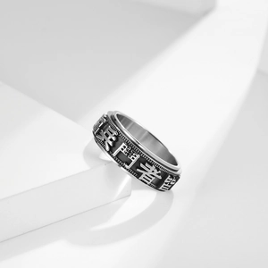 Vintage rotating stainless steel ring with Chinese characters on a white podium