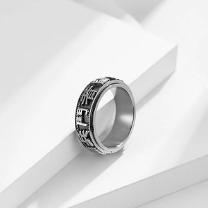 Macro shot of silver rotating spinner ring with vintage Six-Word Mantra engraving