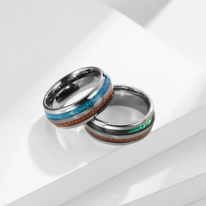 Makroaufnahme von Wolframringen mit Holzmaserung und blauem Opal-Inlay auf weißen Blöcken