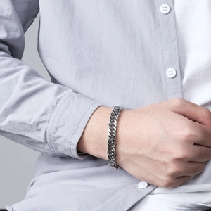 Bracelet unisexe en acier inoxydable argenté porté sur une manche de chemise épurée