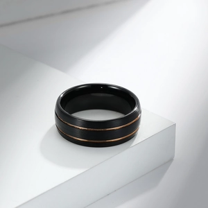 Matte black tungsten steel ring with rose gold lines on a white minimalist display