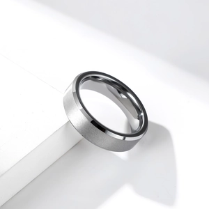 Unisex brushed tungsten wedding ring with polished edges on a white geometric stand