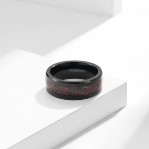 Close-up of men's tungsten ring featuring red carbon fiber dragon pattern on a white stone