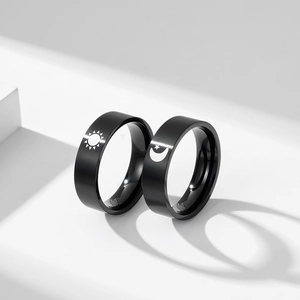 Matte black stainless steel couple rings with sun and moon star engravings on white background