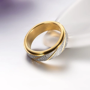 Detail van een gouden draaibare ring met een matte gezandstraalde look en gepolijste lijnen