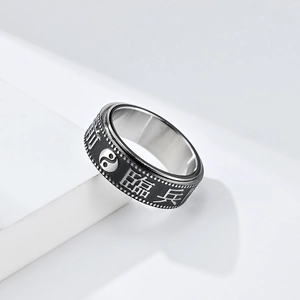Detail view of rotatable black and silver stainless steel anxiety ring with Tai Chi symbols