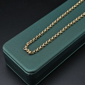 Detailed view of the gold rolo link chain necklace draped on a green jewelry box
