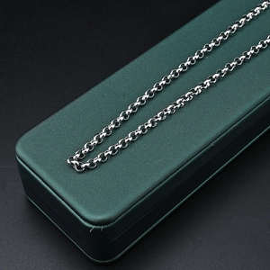 Polished titanium steel chain necklace with round links on a dark green jewelry box