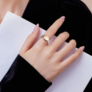 Minimalist polished gold signet ring worn on hand, featuring a sleek flat oval top design