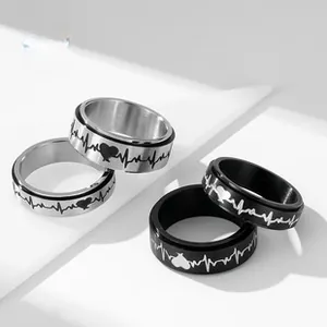 Close-up of stainless steel spinner rings in black and silver with heartbeat engraving