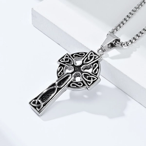 Close-up of vintage Celtic cross pendant with intricate knotwork on metal box chain
