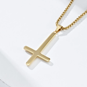 Close-up of golden inverted Saint Peter cross pendant on a square link chain necklace