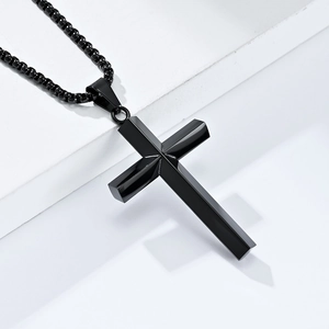 Minimalist black stainless steel cross necklace with matte finish on white geometric background