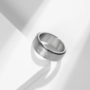 Detailed view of silver spinner ring with brushed texture on white geometric steps