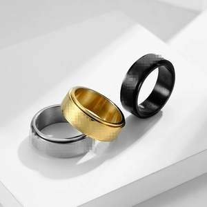 Trio of rotating stainless steel rings in gold, silver, and black on geometric pedestals