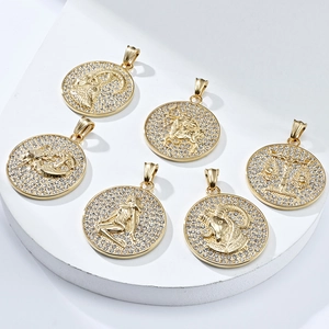 Close-up of gold-plated zodiac pendants with sparkling crystals on a white pedestal
