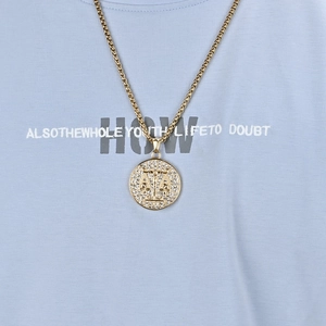 Golden Libra zodiac coin necklace with shimmering zircon pavé stones on blue t-shirt background
