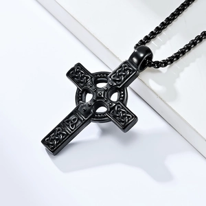 Macro detail of black Celtic cross pendant showing intricate knot textures and matte finish