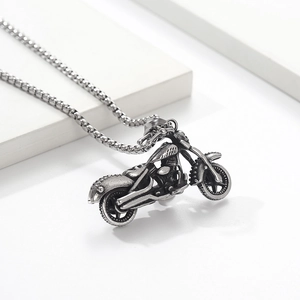 Close-up of vintage oxidized motorcycle pendant with detailed engine and box chain