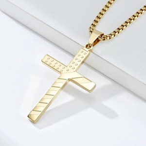 Detail of a golden stainless steel cross necklace with stars and stripes engraving patterns