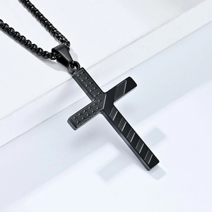 Macro detail of matte black stainless steel cross pendant with star and stripe textures