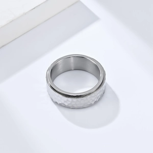 Macro shot of silver hammer-textured stainless steel ring on white geometric background