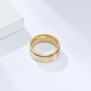 Macro view of a polished wide-band golden spinner ring on a minimalist white backdrop