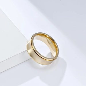 Close-up of a polished golden spinner ring on a white geometric display stand