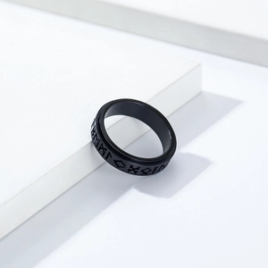Macro shot of black stainless steel ring featuring engraved Norse runes on a white stone base