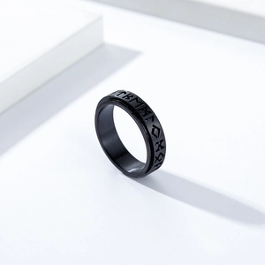 Nordic Viking rune spinning ring in black matte stainless steel on a white pedestal
