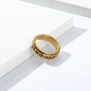 Macro shot of gold vintage Viking runes on rotating stainless steel stress ring surface