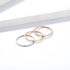 Macro detail of three stackable diamond-cut rings in silver gold and rose gold