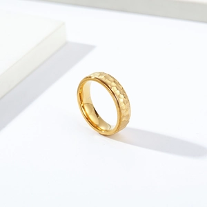 Minimalist hammered gold titanium steel ring with textured finish on geometric display