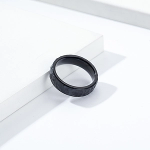Macro shot of black hammered texture titanium steel ring on a white geometric stand