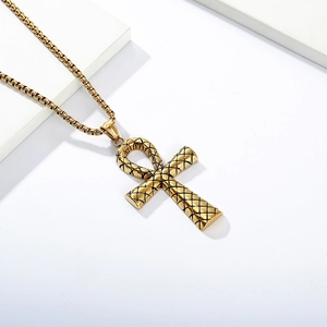 Macro detail of golden Ankh cross pendant with black grid texture on box chain