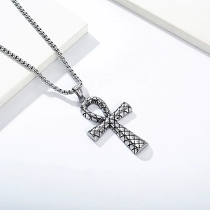 Detail view of vintage silver Ankh cross pendant with intricate diamond pattern texture